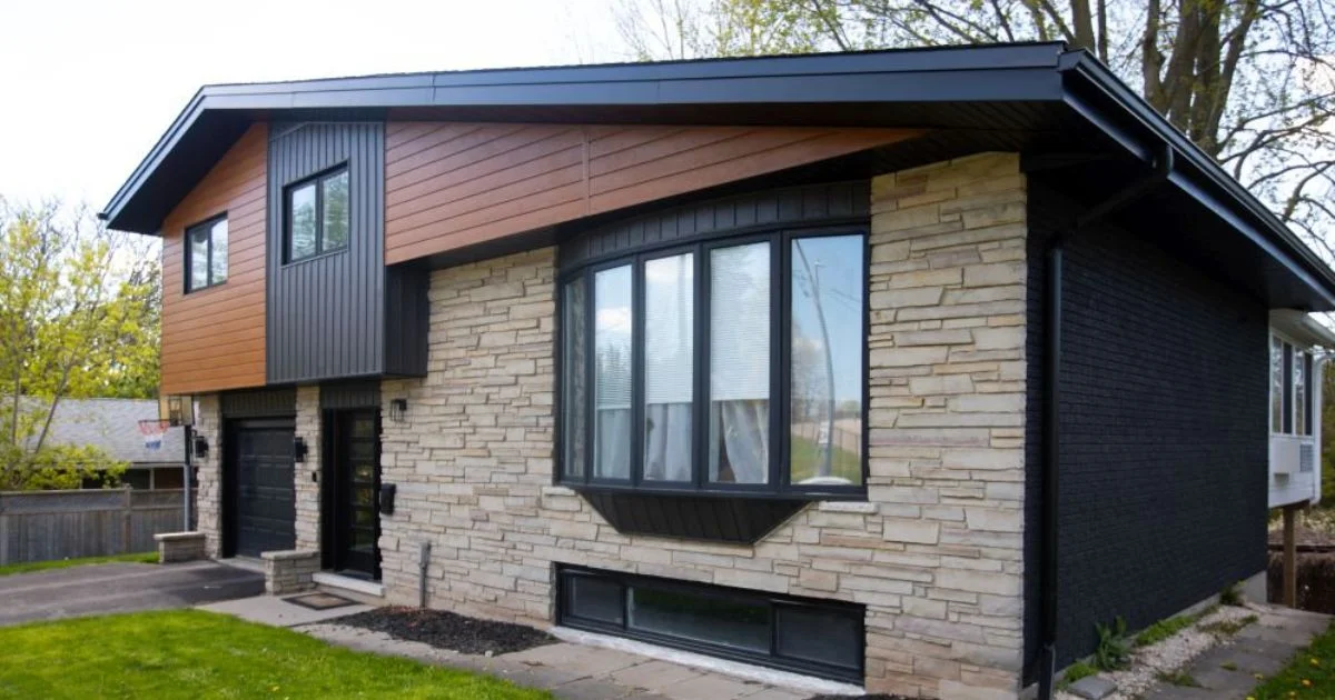 Modern home with mixed exterior siding featuring tan stone, black paneling, and warm-toned wood accents